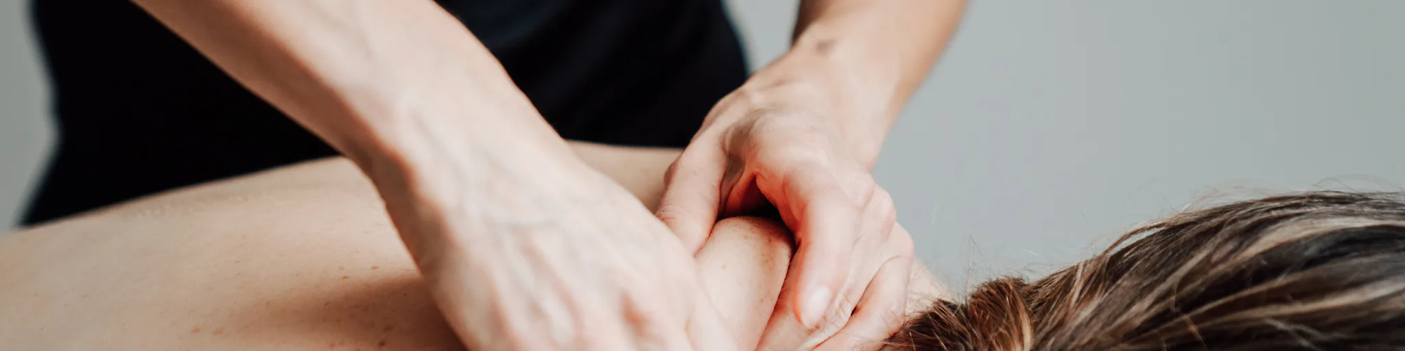 Two hands working on the neck of a person lying on the massage table.