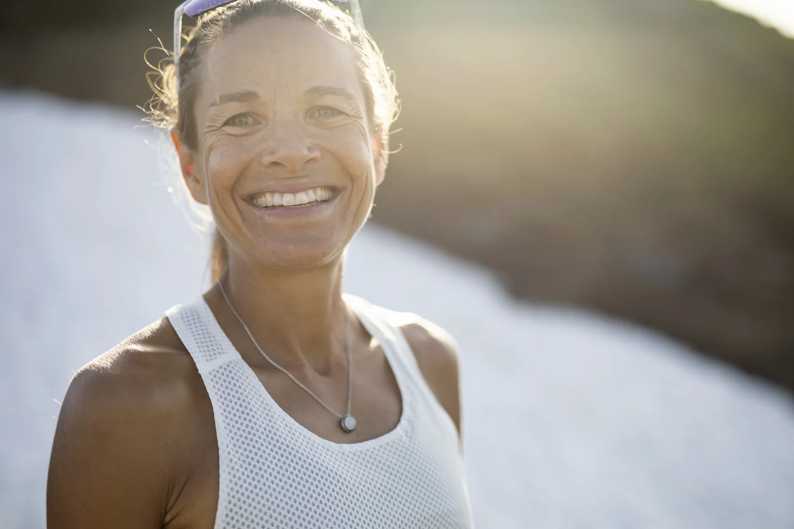 Portrait of Jasmin Nunige in a running shirt in front of a snowfield.